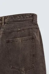 Bermuda de jean color marrón oscuro con efecto lavado, corte amplio, cinco bolsillos y cierre frontal con cremallera y botón.
