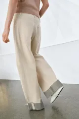 Jeans de tiro medio color beige, corte relaxed leg y largo al tobillo. Cuentan con cinco bolsillos y bajo con vuelta a contraste en gris. Cierre frontal con cremallera y botón.