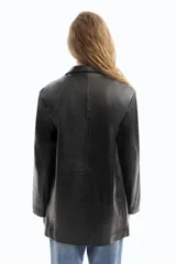 Blazer negro de cuero con solapas de muesca, cierre con un botón, bolsillos delanteros con solapa y corte holgado.