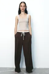 Pantalón ancho gris con textura de espiga, tiro alto, doble cintura elástica ajustable con cordón, pinzas frontales, bolsillos delanteros y falso bolsillo de vivo en la espalda.