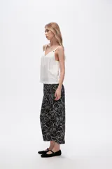 Pantalón capri negro con estampado floral en color crema, de corte ancho y tiro alto.