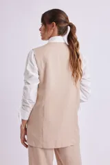 Chaleco largo color beige con solapas, cierre con dos botones y bolsillos delanteros.