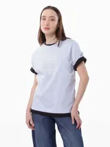 Remera celeste de algodón con cuello redondo y mangas cortas con puños negros. Estampado frontal con el logo de Tommy Hilfiger en color crema.