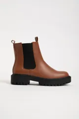 Botas Chelsea color marrón de cuero sintético, con elástico lateral negro, suela track negra y tirador trasero.
