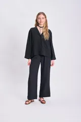 Pantalón negro de corte palazzo, con cintura alta y textura arrugada.