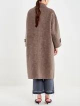 Tapado largo de paño texturado color gris topo, de corte oversize y doble botonadura. Presenta cuello con solapas anchas y mangas largas con puños doblados.