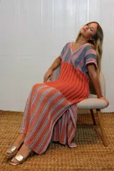 Vestido de tejido de punto con diseño de rayas verticales en bloques de color: superior beige y negro, medio azul y marrón, e inferior beige. Presenta escote en V y mangas cortas.