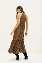 Vestido largo color naranja vibrante con escote halter y cuello con volados. Presenta cintura ajustada con frunces y falda con ruedo con volado.