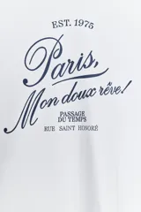 Camiseta blanca de algodón con cuello redondo y mangas cortas. Estampado frontal con la frase "Paris, Mon doux rêve!" en azul marino.