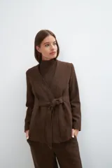 Chaqueta corta color beige, entallada, con escote en V, manga larga y cierre frontal con lazo fijo. Confeccionada en lana fina sin teñir, con bolsillos escondidos y terminaciones enviadas. Hecha 100% en Uruguay.