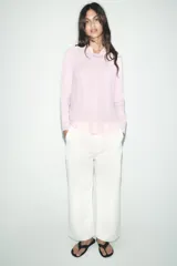 Jersey de punto color borgoña, con cuello redondo, manga larga y bajo con aberturas laterales.