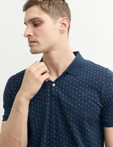 Chomba azul marino con pequeños lunares blancos, cuello clásico con botones y mangas cortas.