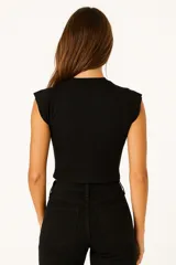 Musculosa negra de algodón con cuello redondo y sisas con volados. Corte ajustado al cuerpo.
