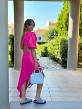 Vestido midi fucsia con escote en V, mangas cortas abullonadas y abertura en la cintura.