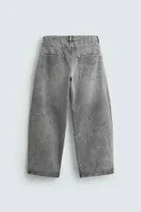 Pantalón de jean gris con efecto lavado, corte amplio tipo balloon fit, tiro medio, cinco bolsillos y cierre frontal con cremallera y botón.