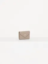 Billetera pequeña color visón, con solapa y cierre a presión. Diseño acolchado con pespuntes en forma de V y logo metálico con forma de labios.