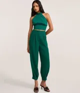 Blusa cropped marrón con escote halter, cuello alto con cierre en el cuello y pliegues en la cintura.