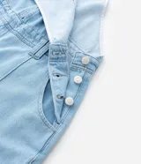 Mono peto de jeans celeste confeccionado en algodón certificado BCI. Tiene breteles anchos ajustables, bolsillos delanteros y traseros, y bajo largo.