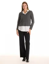 Buzo de tejido fino color gris oscuro con cuello en V, combinado con una camisa blanca que asoma por debajo, simulando un look de dos piezas.