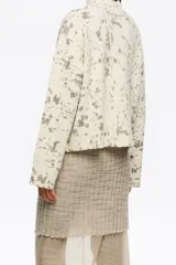 Sweater corto de corte boxy, color crema con estampado moteado en gris/marrón. Presenta cuello alto y mangas largas rectas.