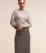 Falda midi de poliéster, viscosa y elastano color negro, de corte recto y tiro alto. Presenta diseño cruzado con hebilla metálica lateral y bolsillo cargo.