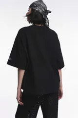 Remera blanca de algodón con cuello redondo y manga corta. Estampado pequeño de un ají rojo en el centro del pecho.