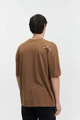 Remera color crema de manga corta con corte boxy, cuello redondo y logo estampado en el pecho.