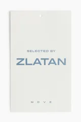 Remera deportiva blanca de manga corta y cuello redondo, con logo de la marca Zlatan en el pecho. Corte ajustado.