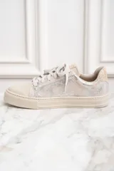 Zapatilla de cuero color beige con detalles metálicos y cierre de cordones.