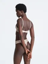 Soutien triangular de encaje color beige, sin aro ni relleno, con breteles regulables y banda elastizada con logo Calvin Klein.