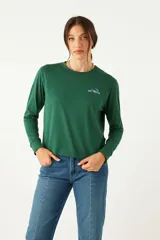 Remera verde de manga larga con cuello bote y estampado frontal con la palabra 'Infinity' en azul.