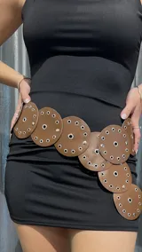 Cinturón marrón de cuero con apliques circulares y ojalillos metálicos.