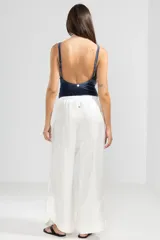 Pantalón blanco de lino italiano con hilo metalizado, corte recto, talle medio, cintura elástica en la parte trasera y bolsillos delanteros.