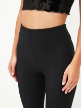 Calza ajustada color rojo oscuro, de tiro alto y tejido acanalado, con corte acampanado en el tobillo.