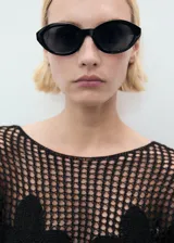 Jersey de punto calado negro con cuello barco y detalles florales bordados.