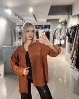 Sobrecamisa color marrón con cuello camisero, cierre frontal con botones, mangas largas con puños abotonados, dos bolsillos de parche en el pecho y ruedo desflecado.