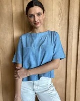 Remera negra con cuello redondo y mangas cortas, con detalle de pespuntes blancos en cuello, mangas, bolsillos frontales y ruedo.