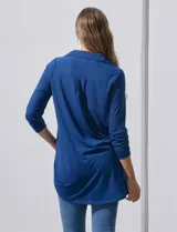Camisola blanca de manga tres cuartos, marca Rio & Rian. Cuello con solapa y abertura central con botones. Manga con detalle fruncido.