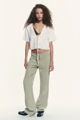 Camisa blanca de manga corta con escote en pico y cierre frontal con lazadas. Presenta bordados florales a tono.
