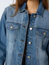 Chaqueta de jean celeste de corte recto con cuello solapa, cierre frontal con botones metálicos, bolsillos de parche con solapa abotonada en el pecho y bolsillos laterales.