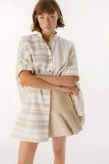 Camisa oversize con cuello mao, manga corta con terminación en puño, botones de metal a la vista y tajos laterales.