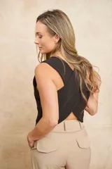 Chaleco negro con escote en V, corte sastrero y tres botones dorados. Diseño cruzado en la espalda.
