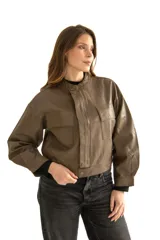 Chaqueta corta de cuero marrón con cuello mao, cierre frontal con botones a presión, dos bolsillos de parche con solapa en el pecho y mangas largas abullonadas con puños elásticos.