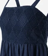 Vestido midi de corte evasé en color azul marino, confeccionado en una mezcla de algodón y lino. Presenta un escote cuadrado con tirantes anchos y un detalle de tejido con efecto crochet en la zona del busto.
