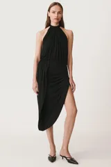 Vestido midi negro de cuello halter y hombros descubiertos. Cintura con elástico, detalle de drapeado lateral y bajo asimétrico. Cierre en cuello con botones.