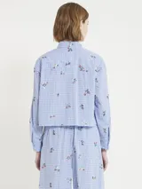 Camisa corta estilo boxy de cuadrillé celeste y blanco con bordado de flores, botones y canesú en la espalda.