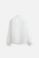 Sobrecamisa verde militar de lino, corte relaxed fit, con cuello solapa, manga larga con puños abotonados, bolsillos de parche con solapa en el pecho, aberturas laterales en el bajo y cierre frontal abotonado.