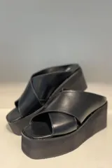 Sandalias negras de cuero sintético con plataforma y tiras cruzadas.
