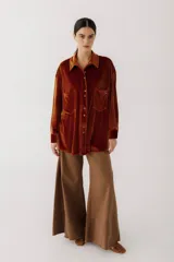 Camisa beige de terciopelo con cuello clásico, cierre frontal con botones, dos bolsillos de parche en el pecho y mangas largas con puños abotonados.