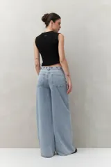 Pantalón de jean negro de corte ultra wide, tiro medio y detalles metálicos en la cintura.